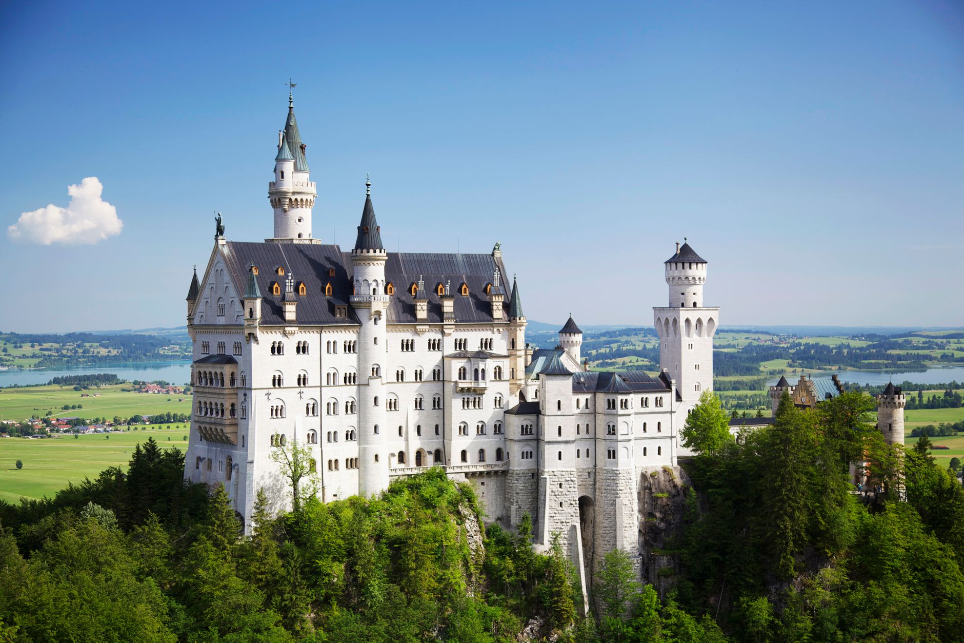 Zamek Neuschwanstein na wzgórzu pośród zielonych lasów Bawarii