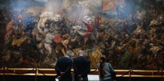 Zwiedzający oglądają wielkie malowidło historycznej bitwy w muzeum