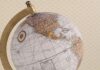 Kolonialne plany II RP – czy Polska naprawdę chciała zdobyć Madagaskar? Stylizowany globus z mapą świata i kompasem na teksturowanym tle